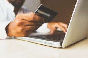 Man holding a credit card as he uses his laptop to shop online.