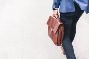Business man carrying brown brief case as he walks away.